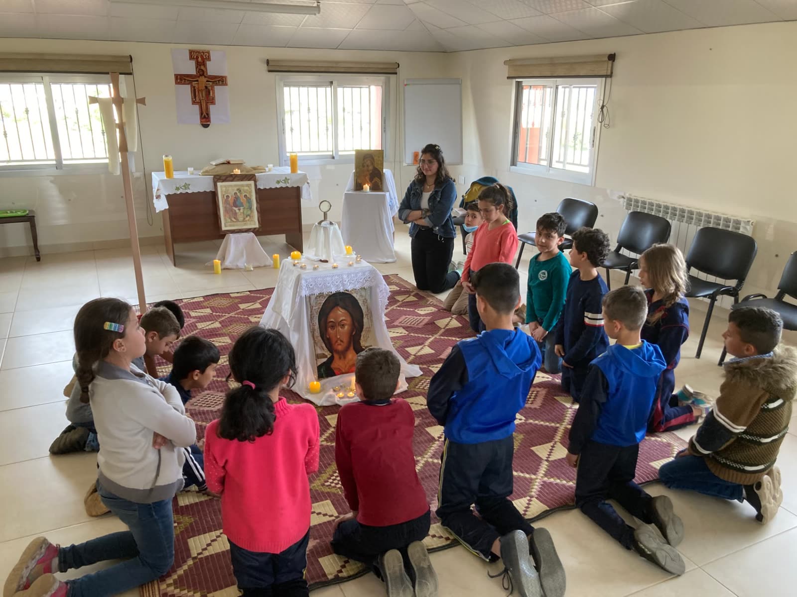 Des enfants à genoux autour d'une icône du Christ pendant un temps de prière de l'Oratoire