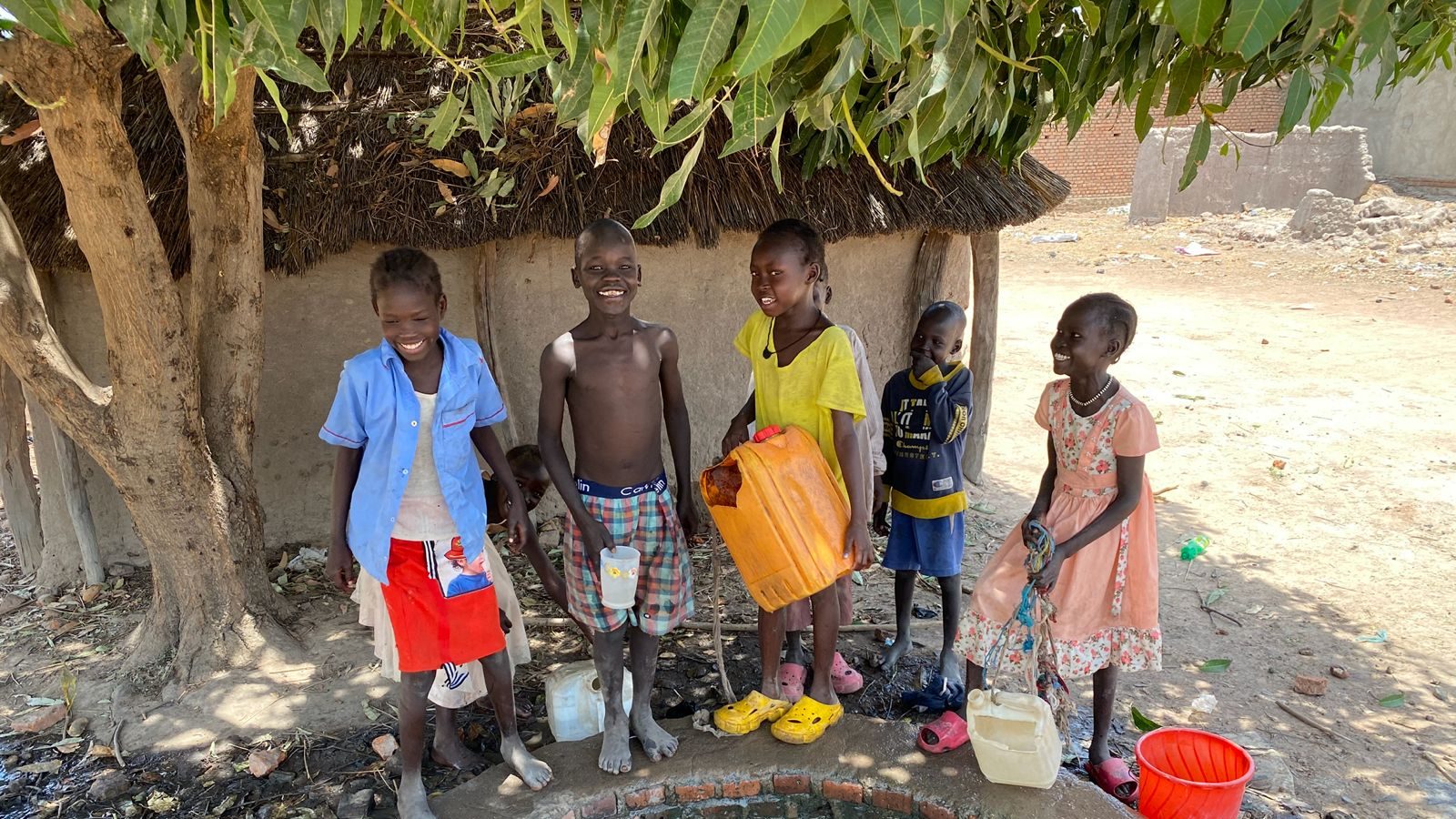 Des enfants rassemblés autour du puits d'un village